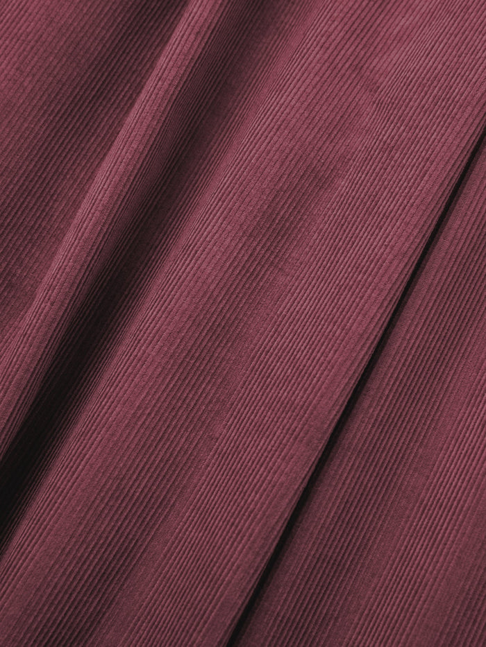 Close-up of maroon corduroy fabric, as featured in the FOUND Corduroy Pleated Trousers, highlighting its vertical ridged texture and natural folds.