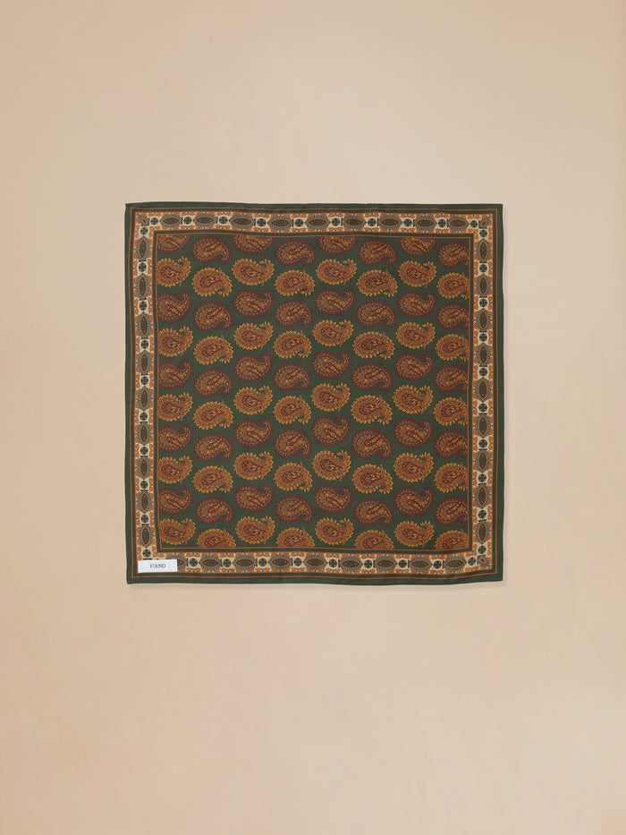 A square cotton blend fabric with a Paisley Forest Bandana print, accompanied by a white tag, made by Found.