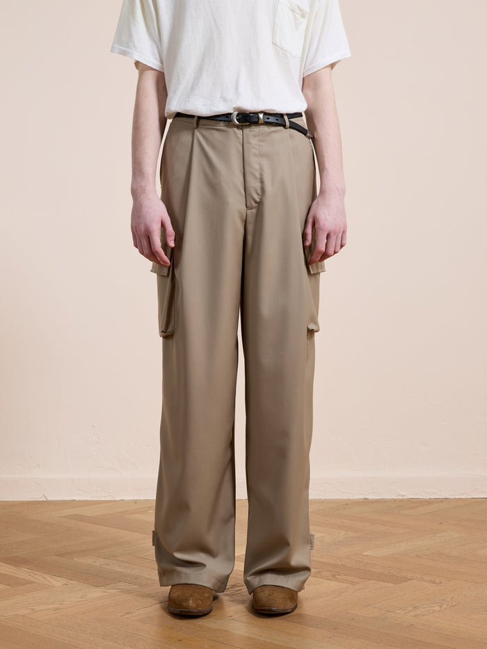 Person wearing FOUND Pleated Cargo Pants, a white t-shirt, black belt, and brown shoes, standing on a wooden floor against a plain light background.