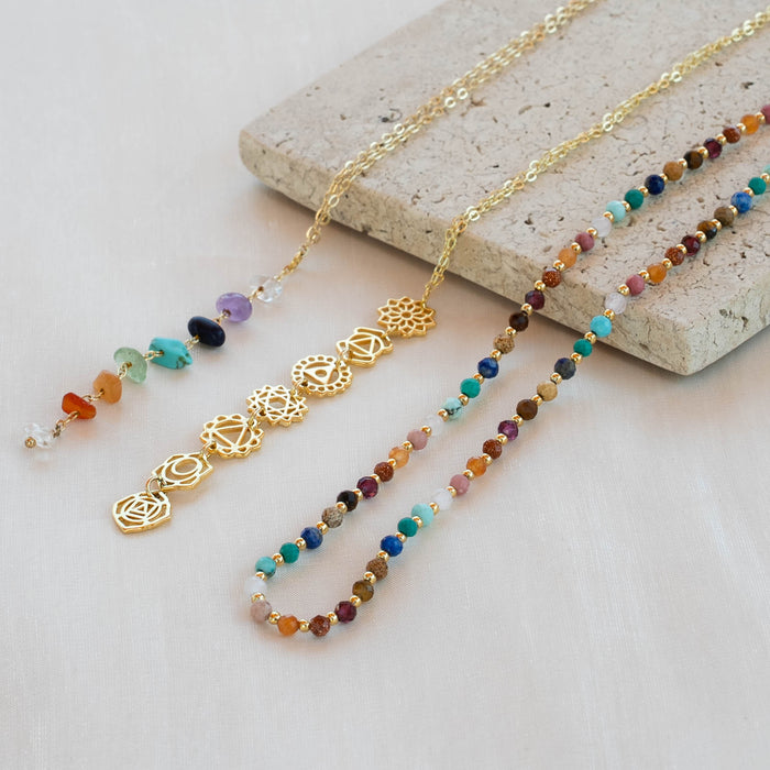 7 Chakras Raw Stone Healing Necklace, flat lay on stone