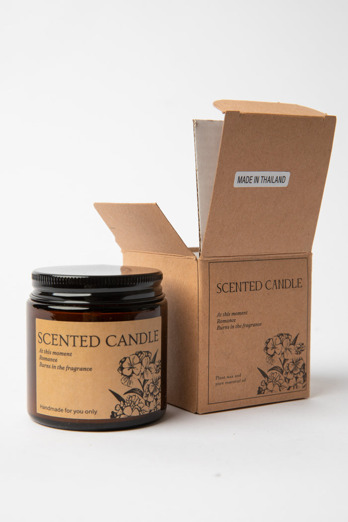 Hand-poured amber glass Apothecary Jar Candle beside open kraft box with black lid
