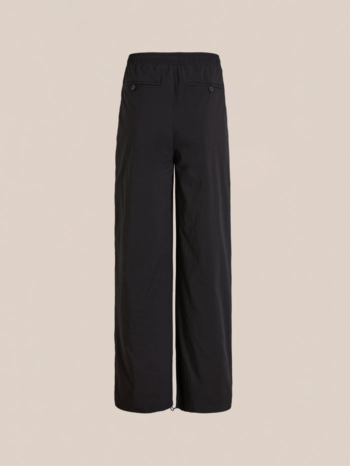 The Found Arena Stripe Track Pants feature a black wide-leg design, adjustable waistband, and two back pockets for versatile unisex sportswear style, shown against a plain beige background.