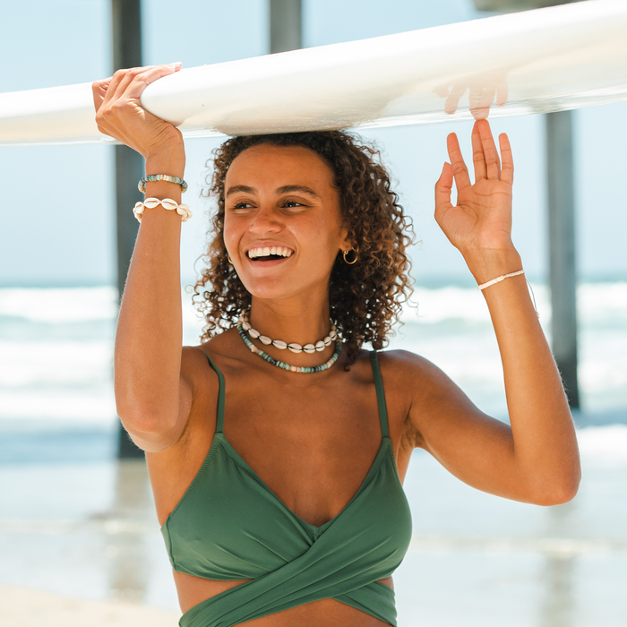Black Cowry Shell Necklace, worn holding surfboard