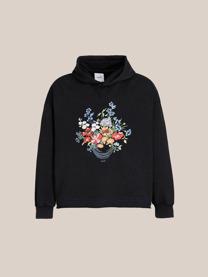 The FOUND Bouquet Flowers Hoodie is black with a vibrant floral bouquet graphic on the front, shown against a plain beige background.