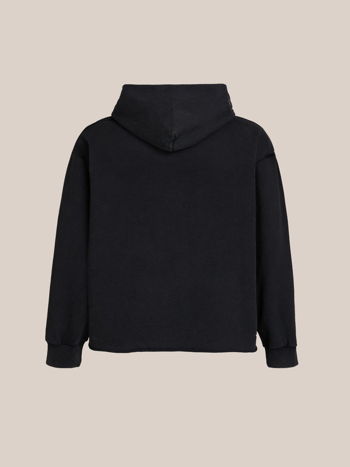A plain black FOUND Bouquet Flowers Hoodie is displayed from the back against a beige background.