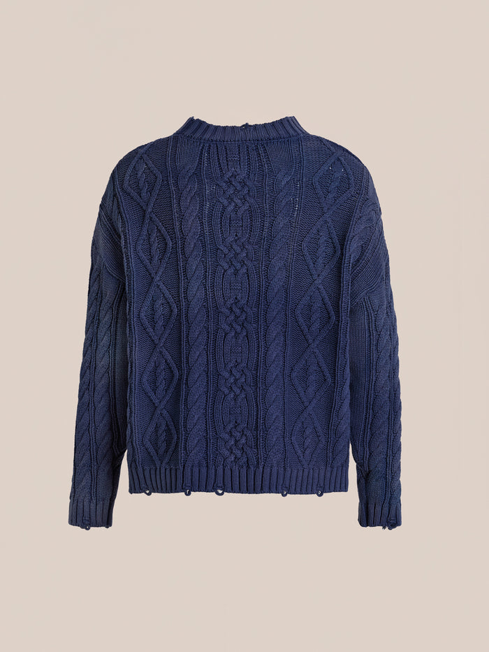 The Found Cable Knit Pullover Sweater is a navy blue unisex style with diamond and braided patterns, long sleeves, and ribbed hem and neckline, shown against a plain beige background.