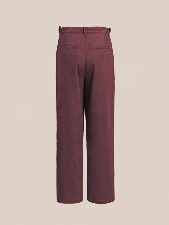 Rear view of the FOUND Corduroy Pleated Trousers in burgundy, showcasing a wide-leg silhouette with belt loops and two back welt pockets, displayed against a plain beige background.