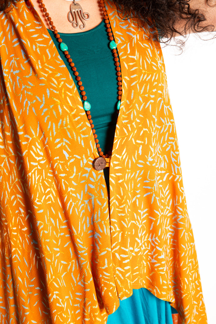 Susan wearing a long orange batik patterned vest in turmeric