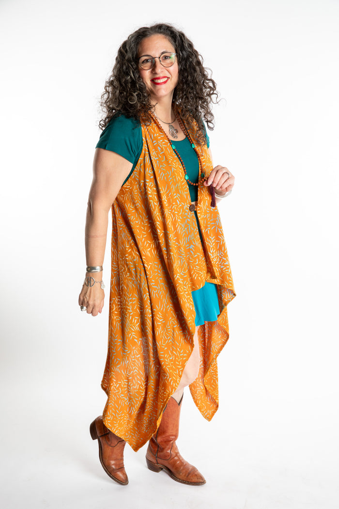 Susan wearing a long orange batik patterned vest in turmeric