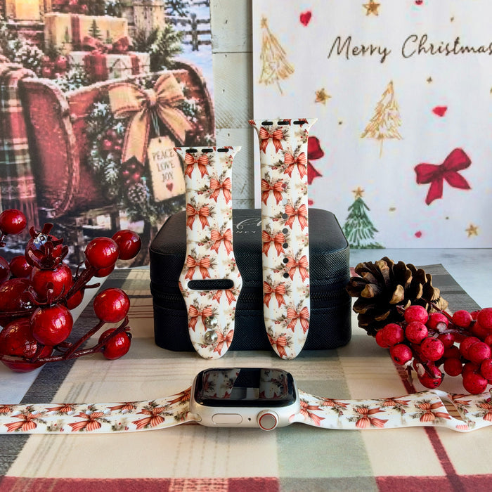 Deck The Halls With Bows & Holly Apple Watch band shown on an Apple Watch and as two straps on a black jewelry box, red ribbon bows and holly on ivory