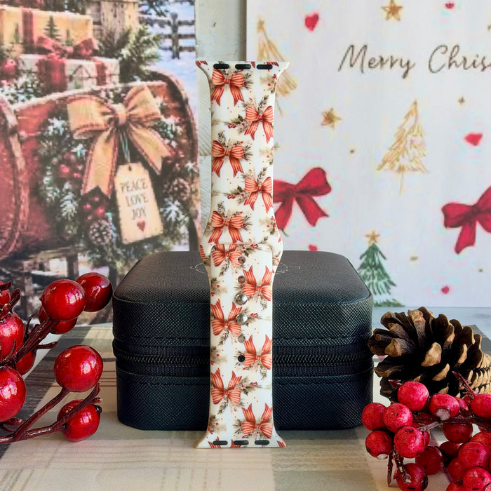 Deck The Halls With Bows & Holly Apple Watch band buckled and standing on a black jewelry box between red berries and a pinecone