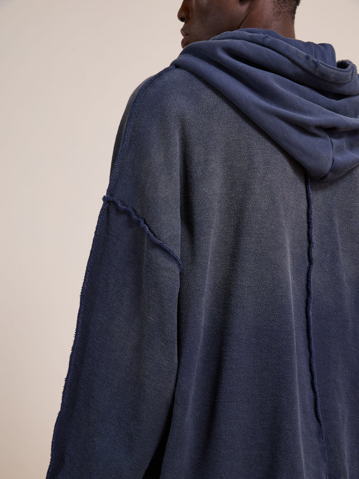 A person wearing the FOUND Deconstructed Terry Zip Up Hoodie in relaxed fit navy blue with exposed seam details, shown from the back and side.