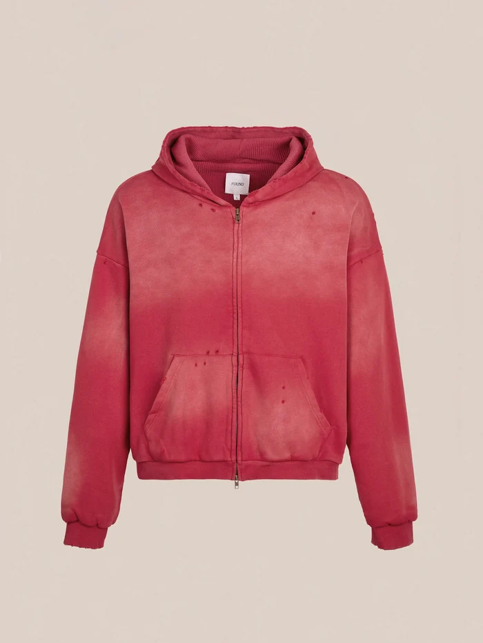 The FOUND Distressed Thermal Lined Zip Up Hoodie features a red faded look, unisex relaxed fit, front pockets, ribbed cuffs, and a hood, shown against a plain beige background.