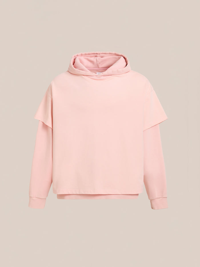 The Found Double Layer Hoodie features a light pink hue, long sleeves, and a unisex relaxed fit in soft French terry cotton, shown on a plain beige background.