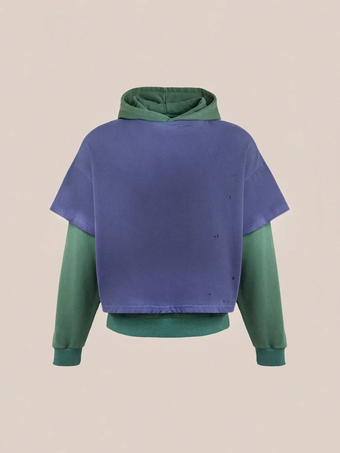 Introducing the "Double Layer Hoodie" by Found: a stylish piece crafted from French terry cotton, showcasing a green hood and sleeves paired with a purple short-sleeve overlay for a vintage look against its plain backdrop.