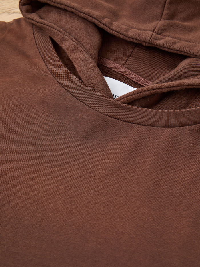 Close-up of the Found Double Layer Hoodie in brown, laid flat to show the hood, neckline, and part of the inner tag for a cozy vintage look.