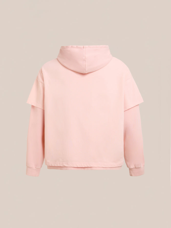 The Found Double Layer Hoodie in light pink French terry cotton, featuring a relaxed unisex fit, is displayed from the back against a plain beige background.