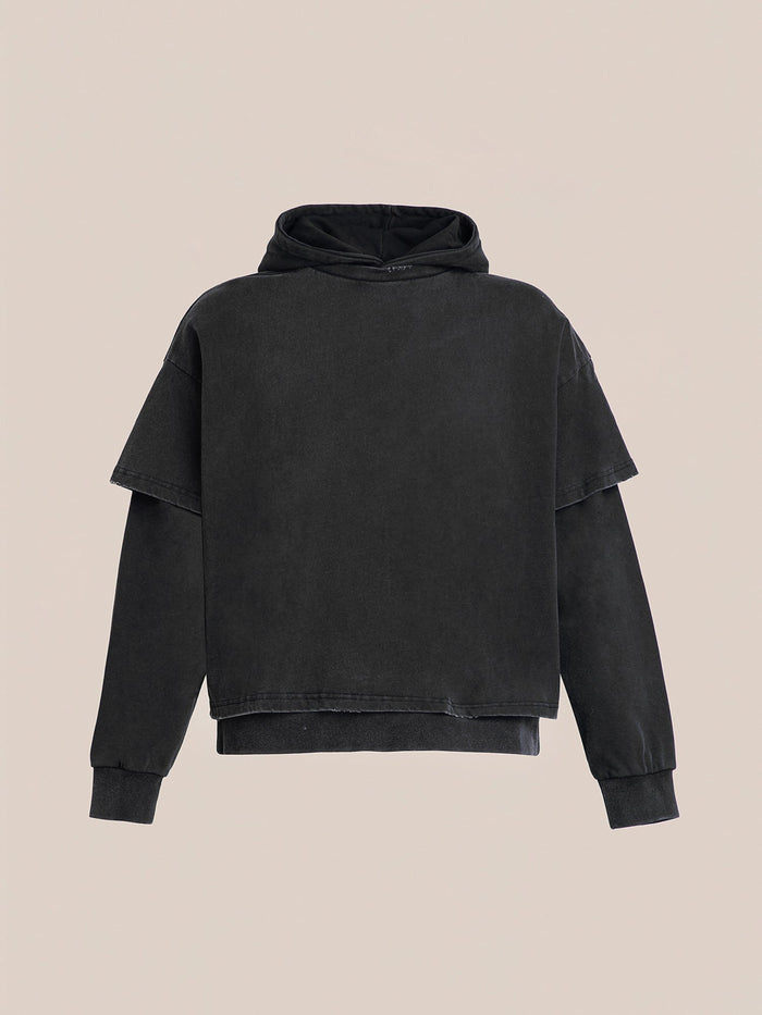 The Double Layer Hoodie by Found is a black, French terry cotton hoodie showcasing a vintage design with its short sleeves over long ones, set against a plain background.