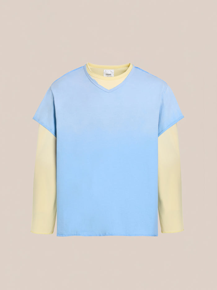 The FOUND Double Layer LS Tee is a unisex long sleeve shirt with cream sleeves beneath a light blue sunfade wash V-neck, shown on a plain beige background.