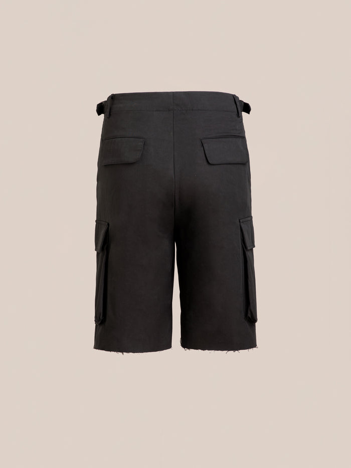 Found Elbas Cargo Shorts shown from the back with adjustable waist tabs, side cargo pockets, two back flap pockets, and a raw hem, set against a plain beige background.