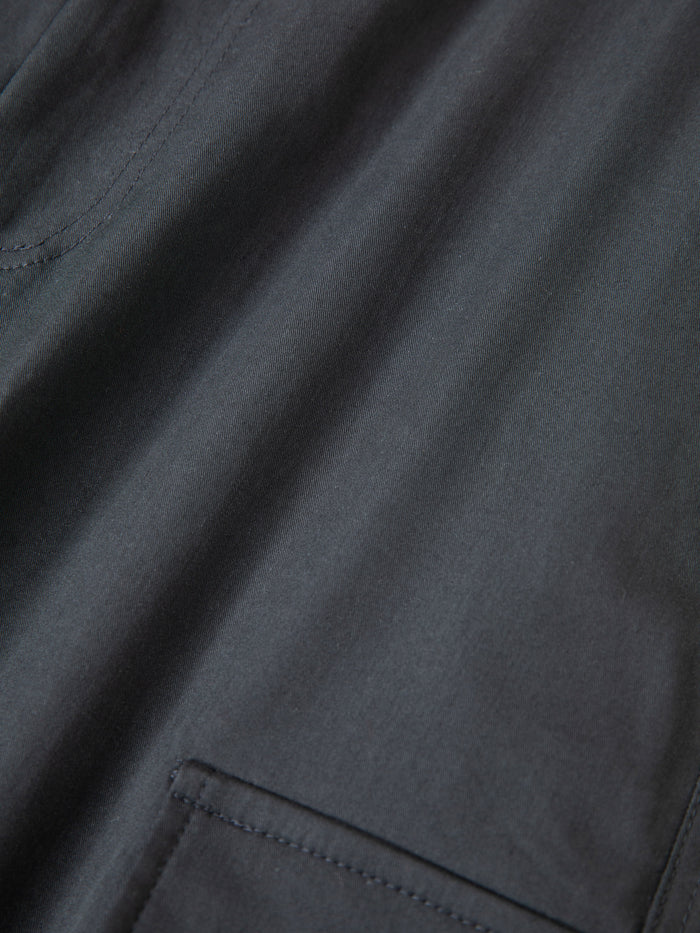 Close-up of a dark fabric garment from Found's Elbas Cargo Shorts, featuring visible stitching, part of a pocket, and adjustable waist tabs.