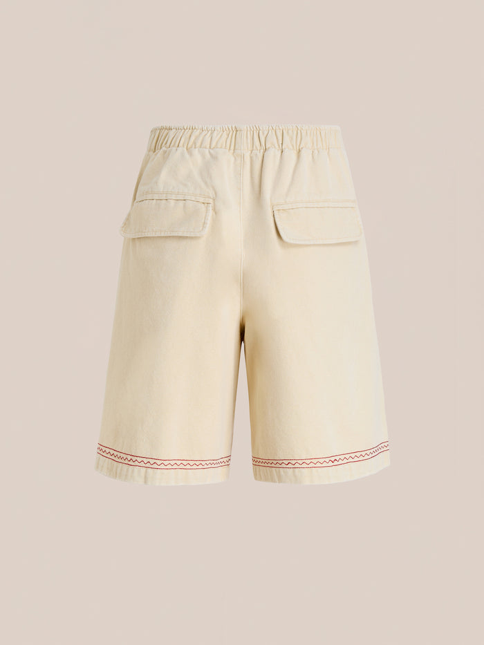 Profound Embroidered Horse Shorts in beige cotton twill feature an elastic waistband, two back flap pockets, and red embroidery near the hem, displayed on a plain background.
