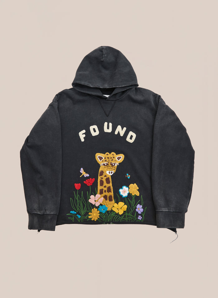 Discover the Embroidered Wildlife Hoodie by FOUND—an elegant black hoodie featuring beautifully embroidered cartoon giraffe, flowers, and butterflies with signature “FOUND” text on the front. Crafted from vintage French-terry cotton, this hoodie effortlessly blends comfort and style, making it a playful addition to your wardrobe.