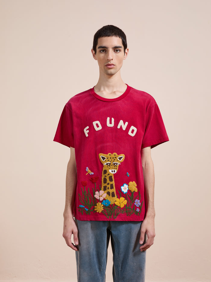 A person stands facing forward wearing the FOUND Embroidered Wildlife Tee, featuring a leopard and floral embroidery. The background is plain and light-colored.