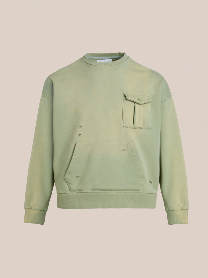 The Faded Pocket Crewneck by FOUND is a heavyweight cotton green sweatshirt with a vintage-inspired, unisex relaxed fit. It features a chest pocket, front pouch, and slightly distressed fabric with small holes.