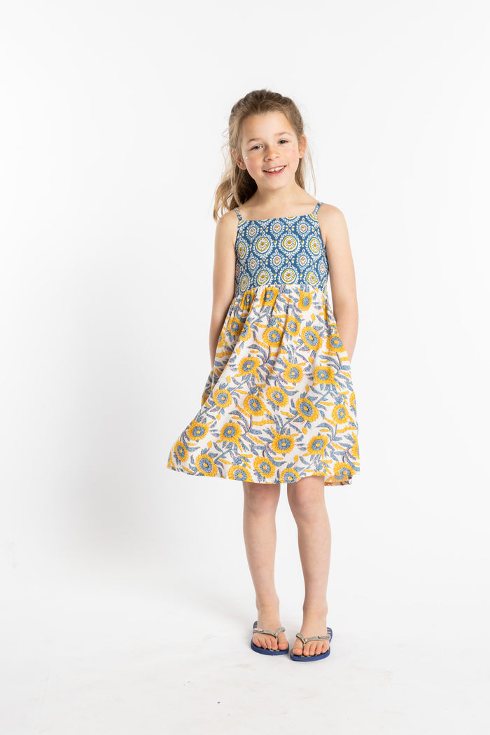Louisa is wearing the size M sunflower floral kids dress with smocked back