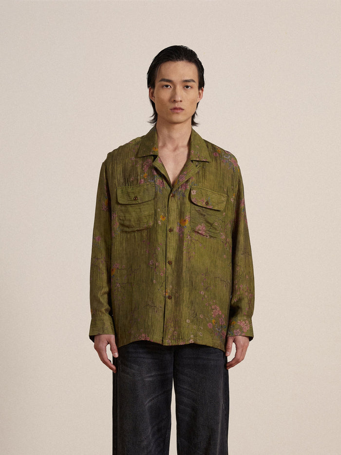 A man wearing a Found Floral Moss Long Sleeve Camp Shirt and black pants.