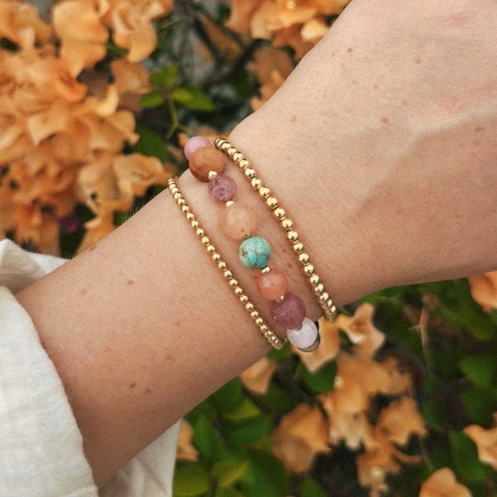 Gold 3mm Stretch Bead Bracelet, on wrist with blossoms