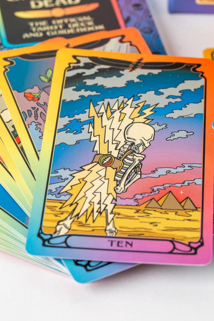 Colorful tarot cards from the Grateful Dead deck showing skeleton and lightning bolt artwork.