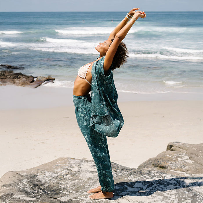 Jade Dahlia Harem Pants, worn in a yoga pose on the beach