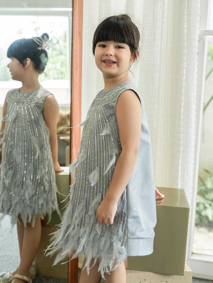 Young girl wearing a silver beaded dress with feather details