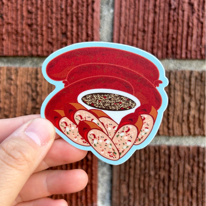 Hand holding a sticker of a red and white design against a brick wall background