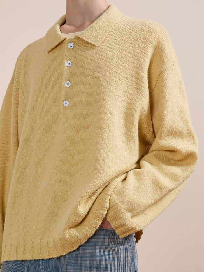 Model wears the FOUND Knit LS Polo Sweater in yellow, made from soft brushed knit with white buttons, styled with light blue pants against a plain background.