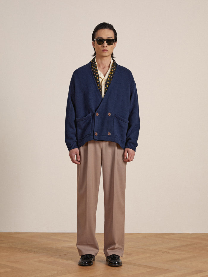 A man wearing a blue Larsi Double Breasted Knit Cardigan and tan pants by Found.