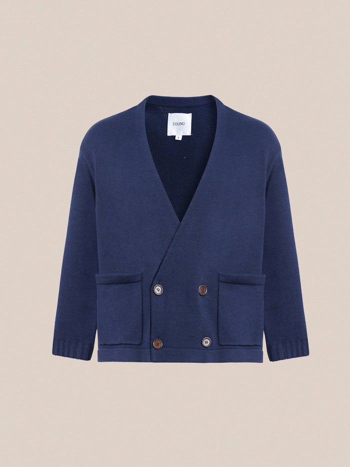 The Larsi Double Breasted Knit Cardigan by Found, in dark blue, features elegant wooden buttons and two front pockets, displayed on a neutral background.