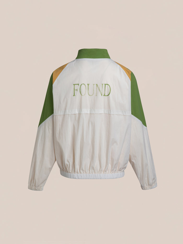 Back view of the Legacy Cricket Track Jacket, featuring a white and green design with "FOUND" branded on it, reminiscent of vintage athletic gear.