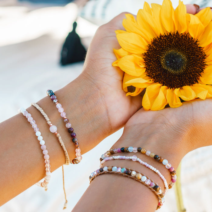 Love + Happiness 4mm Healing Bracelet, stacked on wrist with sunflower