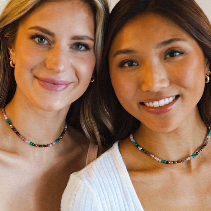 Two girls wearing matching healing necklaces. The necklace is a 6mm multicolor stone healing necklace
