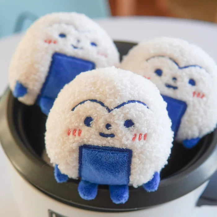 Three plush toys resembling cartoon characters with blue bodies and white faces on a white appliance.