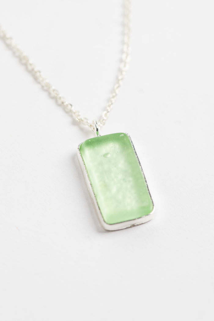 minimalist boho necklace pendant in green on white background