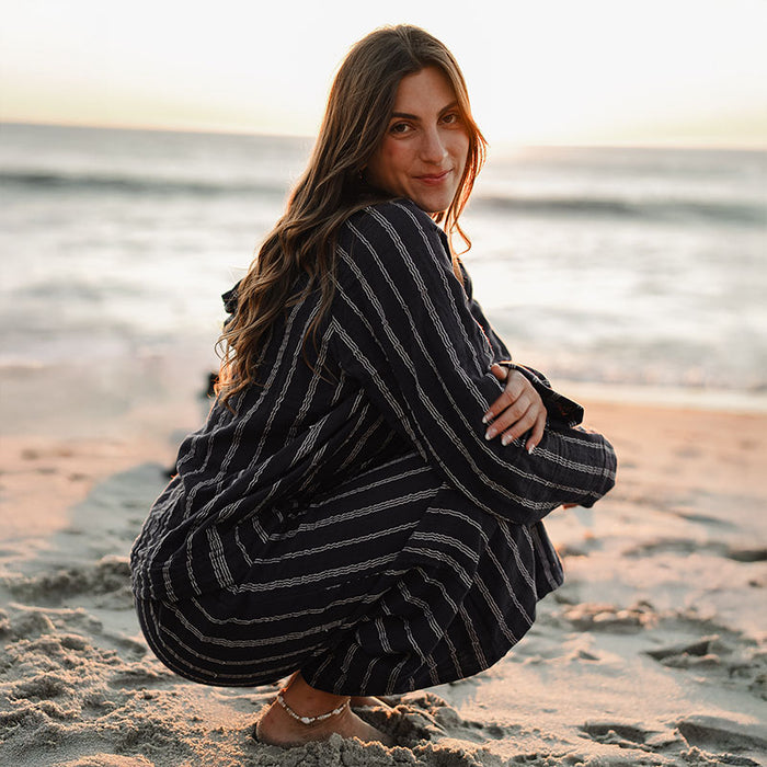 Navy Sailor Stripe Baja Pullover, crouching on the beach