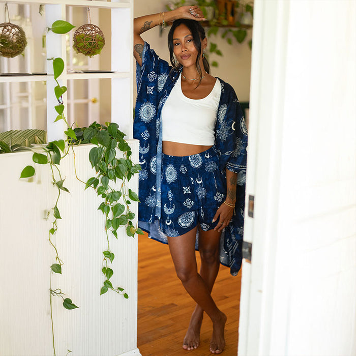 Nightfall Blue Lotus Moon Shorts, worn in a doorway