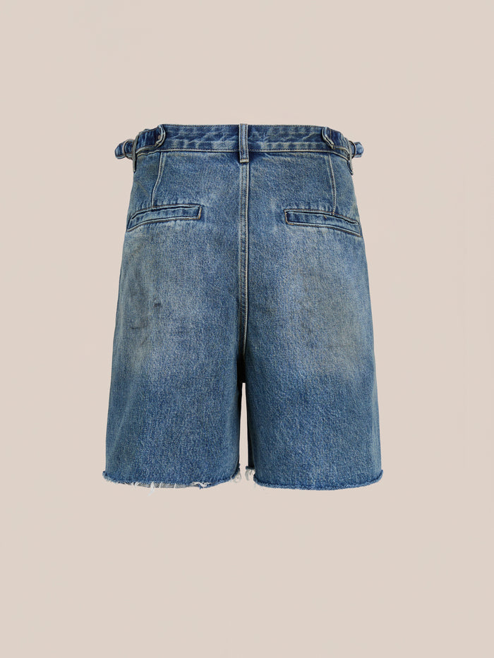 Back view of Found's Paint Studio Denim Shorts in vintage blue with frayed hems, two back welt pockets, and belt loops, shown against a plain beige background.