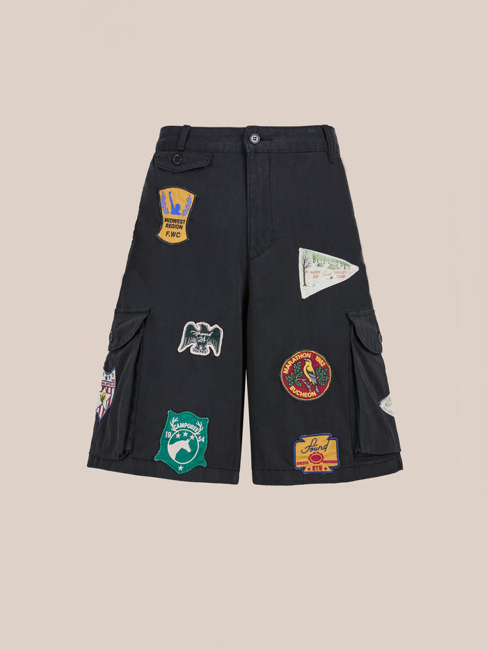 Found Patchwork Cargo Shorts: unisex relaxed fit in vintage black wash with multiple colorful embroidered patches on the front and side pockets, showcased against a plain background.