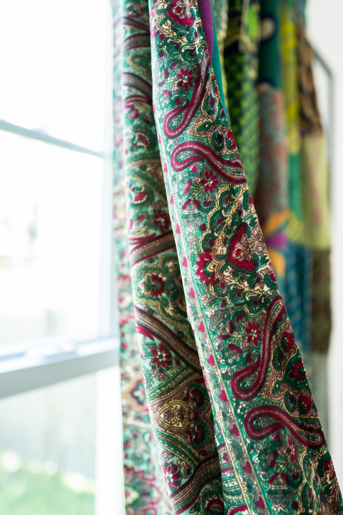 Close-up of a colorful Green patterned fabric with a blurred background. This displays the back of the patchwork curtain.