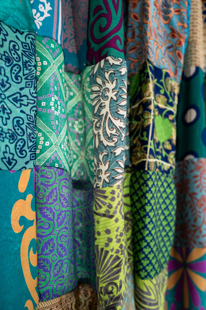 Close-up of colorful green patchwork curtain with various patterns and colors.